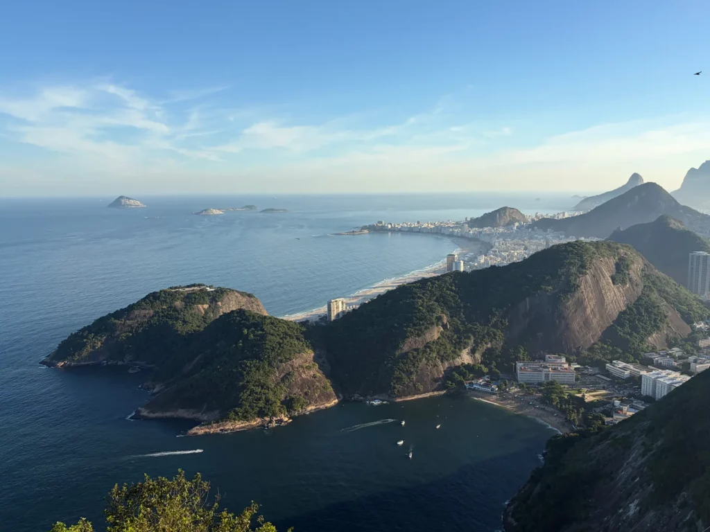 Une vue panoramique sur le littoral de Rio de Janeiro, avec ses collines verdoyantes, ses plages de sable et ses bâtiments en bord de mer, sous un ciel bleu limpide : un décor idéal pour trouver l'inspiration sur ce qu'il y a à faire à Rio de Janeiro en 3 jours.