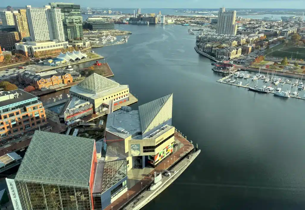 Vue aérienne de l'Aquarium national et du port de Baltimore, un lieu très prisé pour savoir que faire à Baltimore, avec en arrière-plan les jetées, les bateaux et la silhouette de la ville.